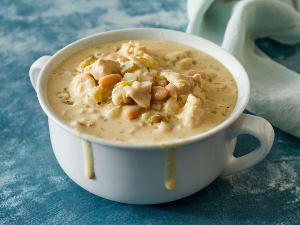 A warm bowl of creamy white chicken chili topped with fresh cilantro and a sprinkle of cheese.
