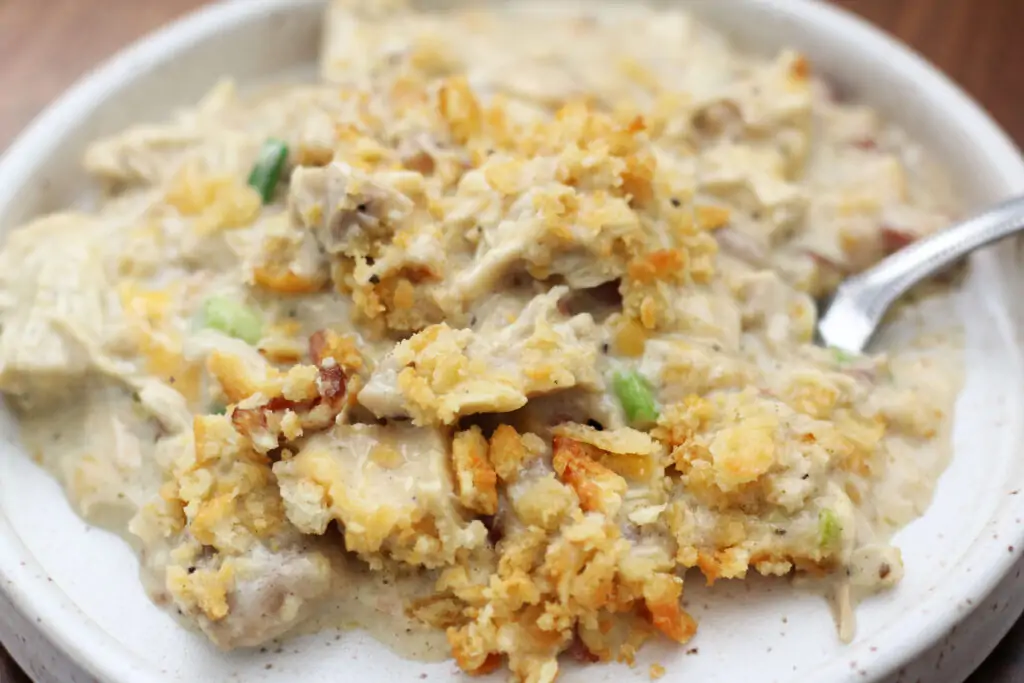 Freshly baked Neiman Marcus Chicken Casserole in a white dish with a golden cracker topping and cheesy, creamy filling visible.